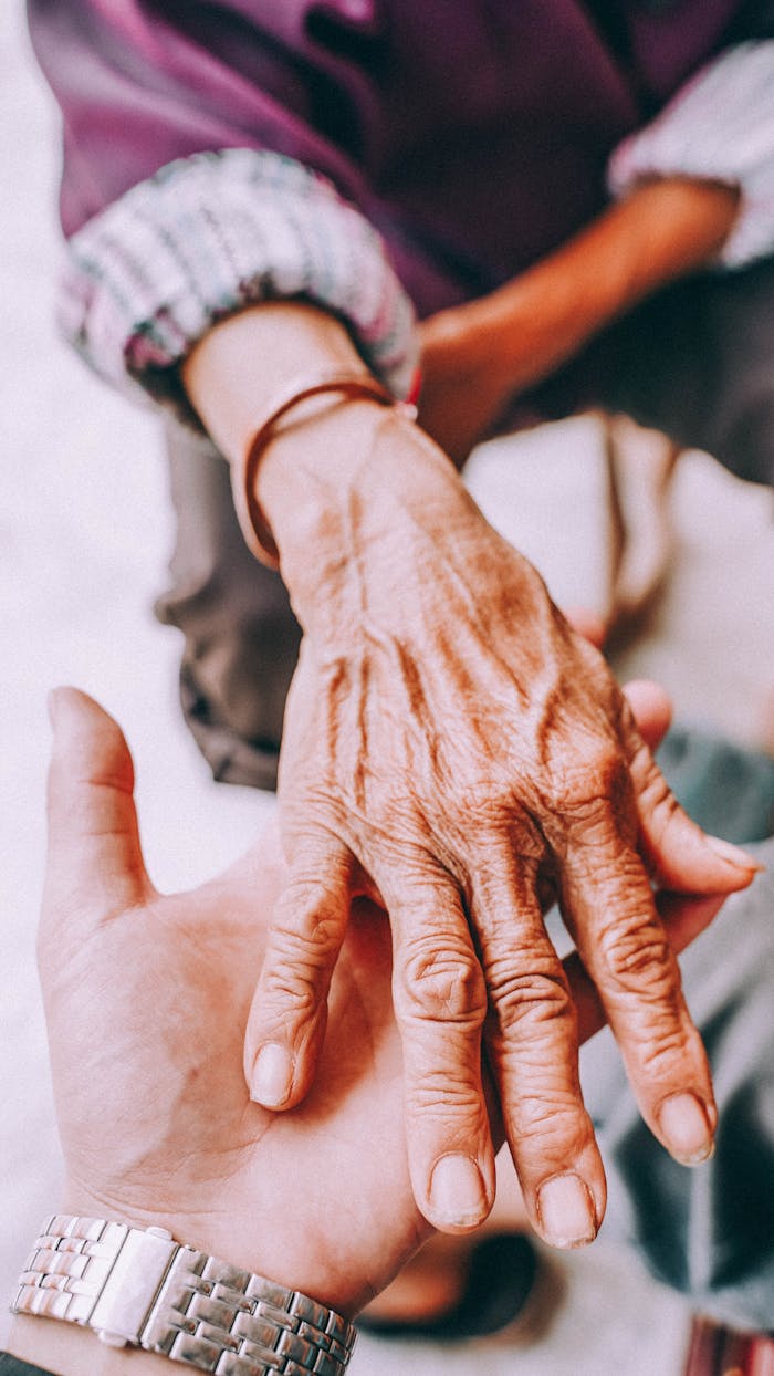 Close-up of a senior's hand being held by a younger hand, symbolizing care and connection.